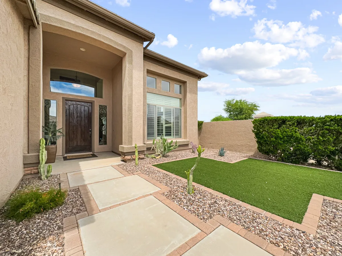 A welcoming front door framed by lush landscaping and a well-maintained pathway leads to the home, suggesting the threshold between private luxury and the vibrant community beyond. The greenery and inviting walkway evoke the sense of transition from personal space to shared outdoor environments.