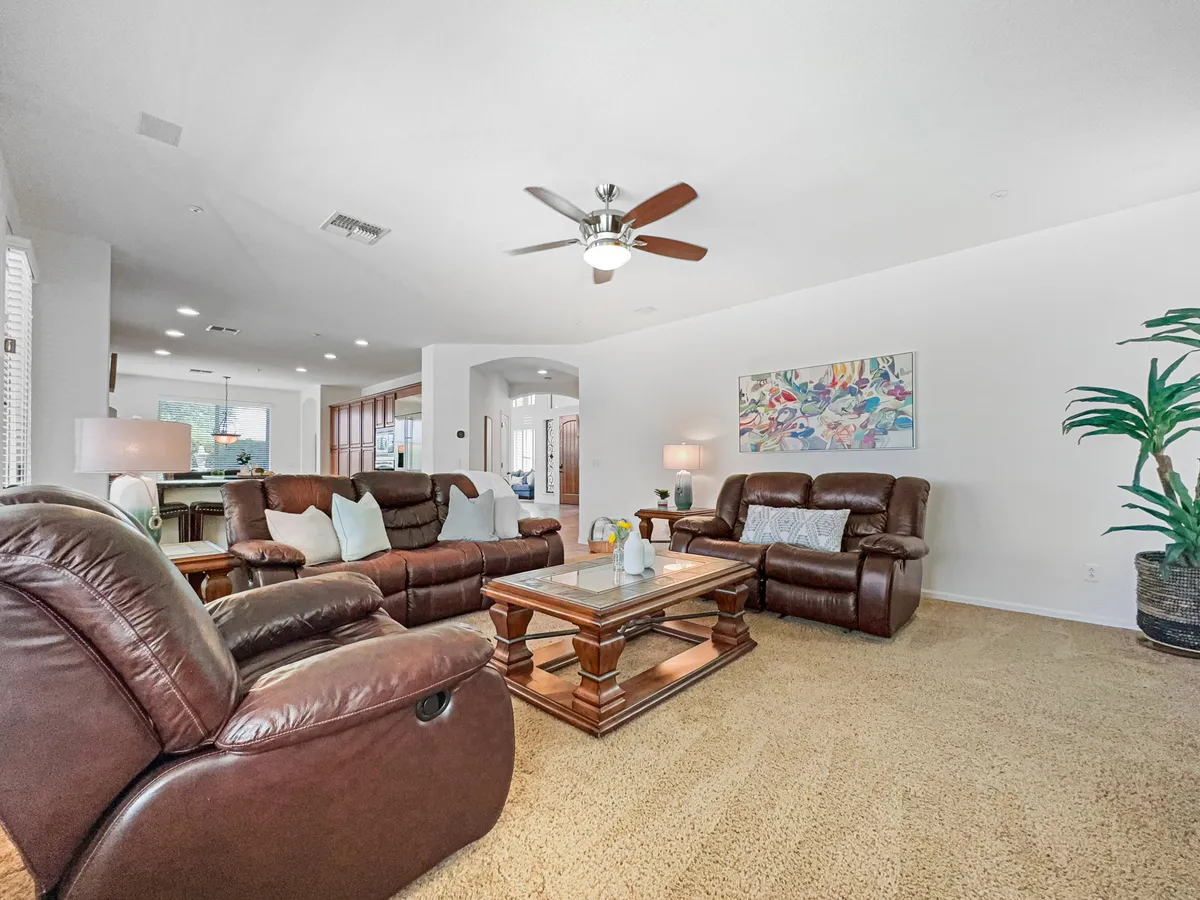 This cozy family room features comfortable reclining sofas, a wooden coffee table, decorative artwork, and indoor plants. The setup is ideal for movie marathons, game nights, or unwinding with loved ones, fostering a sense of connection and relaxation.