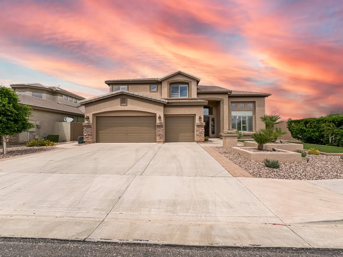 An inviting view of the home's front entrance, garage doors, and a landscaped yard, all set against a softly glowing sunset sky. The spacious driveway and front porch suggest opportunities for outdoor activities, evening barbecues, and gathering with neighbors and friends.