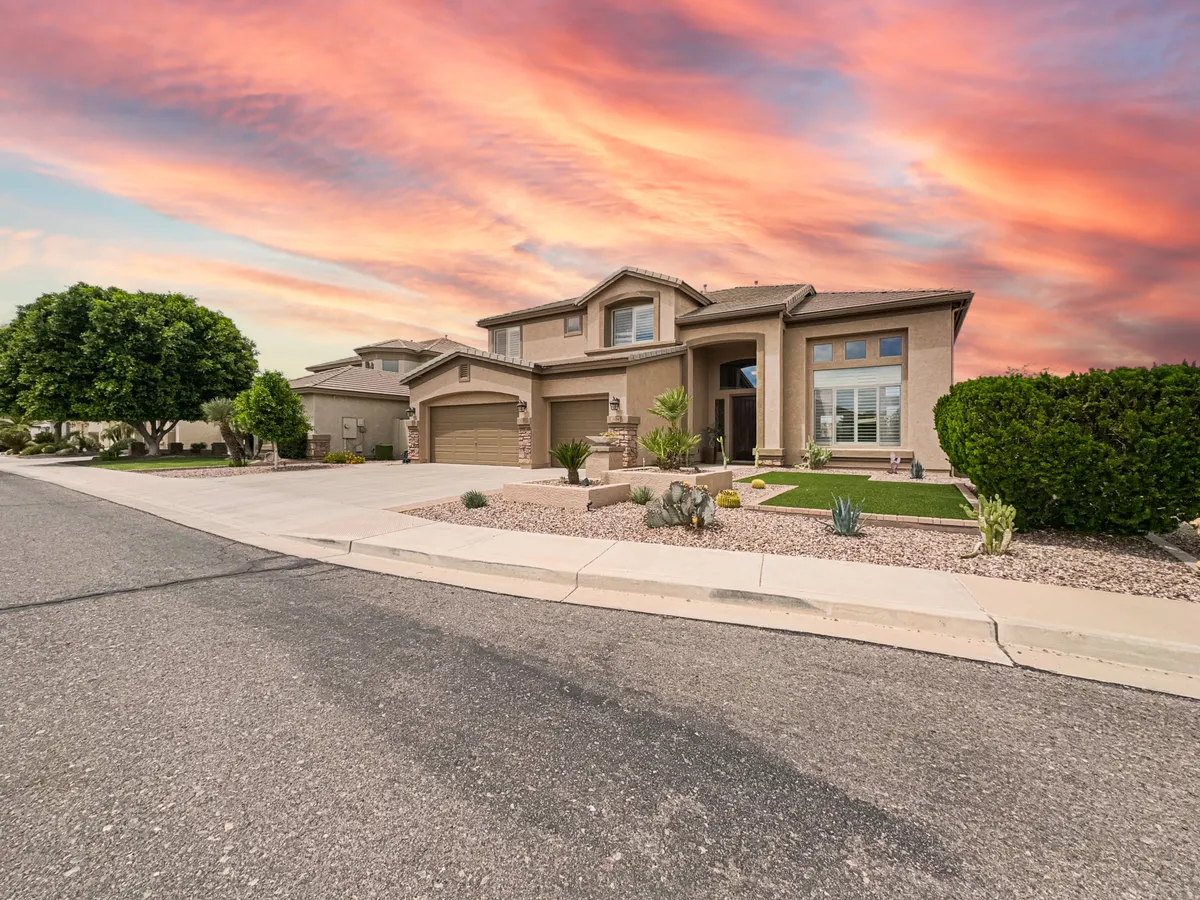 A striking sunset over a well-manicured front yard, with the stylish home set against a serene sky. The scene hints at community life with potential for neighborly gatherings, gardening, and enjoying outdoor activities in a peaceful neighborhood setting.