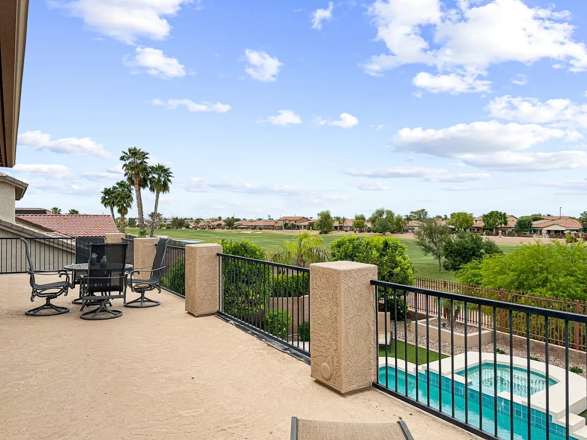 An expansive backyard features an inviting outdoor seating area, sparkling swimming pool, and a scenic view of the golf course framed by palm trees. The relaxed setup welcomes social gatherings, family fun, and tranquil moments against the backdrop of lush greenery and leisure amenities.