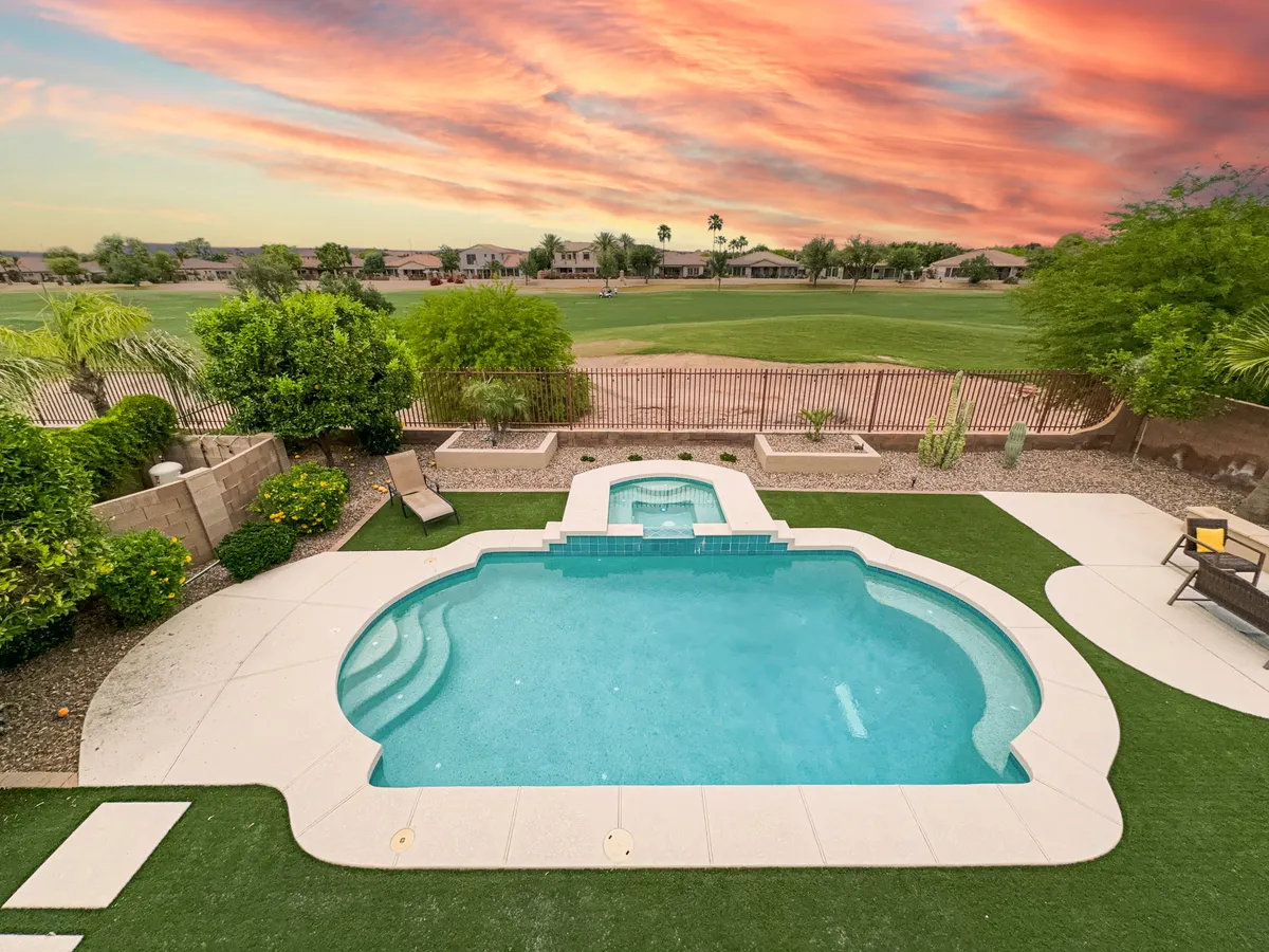 This exterior image features a sparkling swimming pool and a jacuzzi surrounded by lush greenery, with a direct view of the golf course in the background. The scene is serene, capturing the connection between the home’s outdoor leisure spaces and the Seville Golf and Country Club. The inviting poolside setup suggests an ideal spot for watching the golf action or enjoying tranquil mornings by the water.